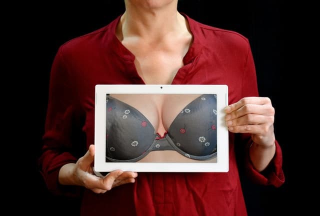 一个女人拿着一张照片，她的乳房在推起胸罩的照片。
