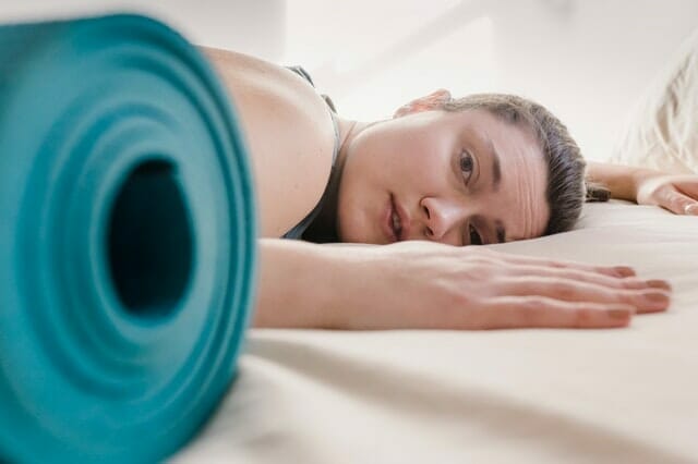 训练后疲惫不堪的女人，在运动垫旁边