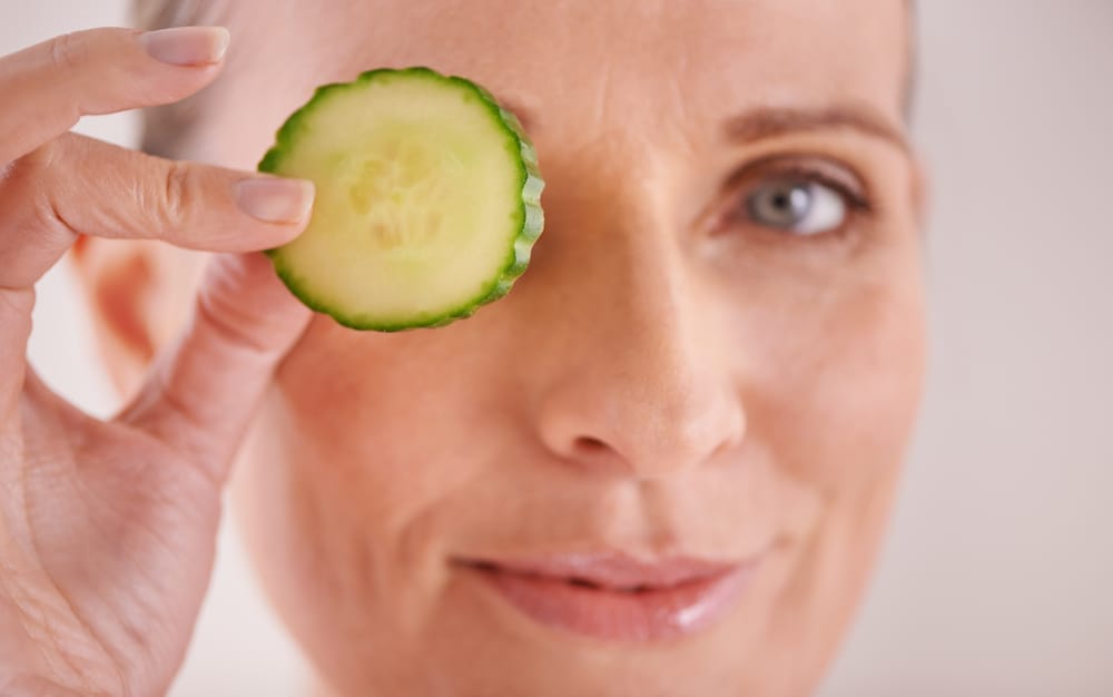 一位女士拿着黄瓜片对着自己的眼睛